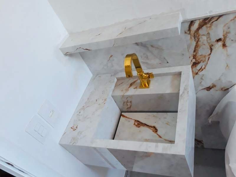 Lavatório de luxo em mármore branco com torneira dourada